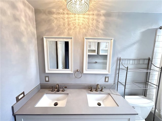 bathroom featuring toilet, double vanity, and a chandelier