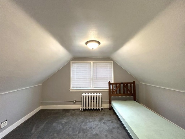 additional living space featuring radiator, vaulted ceiling, dark carpet, and baseboards