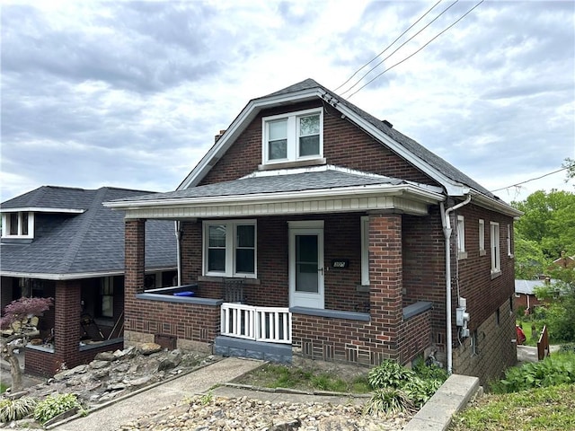 view of front of house featuring a porch, brick siding, and a shingled roof