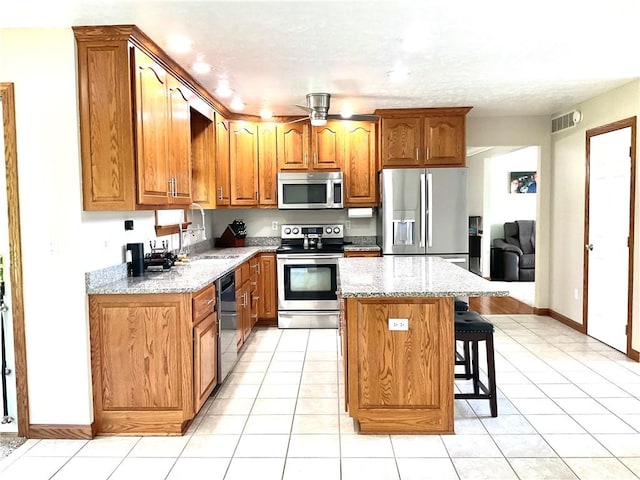 112 Pheasant Ridge Dr, Center Twp But, PA 16001 - kitchen featuring stainless steel appliances, brown cabinetry, a sink, a kitchen breakfast bar, and a kitchen island