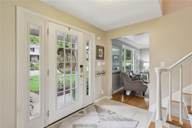 tiled foyer entrance with stairs, crown molding, and baseboards