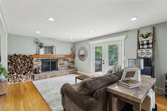 living area with a stone fireplace, hardwood / wood-style flooring, recessed lighting, baseboards, and french doors
