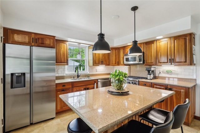 kitchen with appliances with stainless steel finishes, a sink, brown cabinets, light stone counters, and decorative backsplash