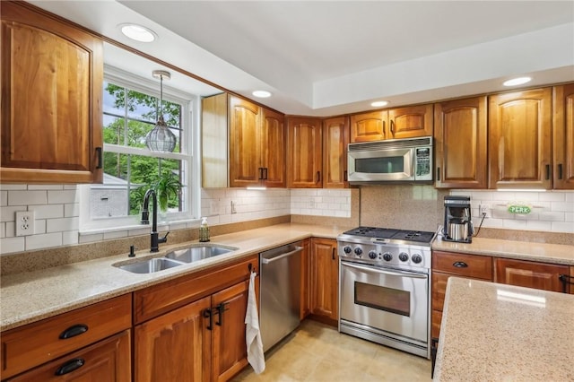kitchen with appliances with stainless steel finishes, a sink, brown cabinets, light stone countertops, and decorative backsplash