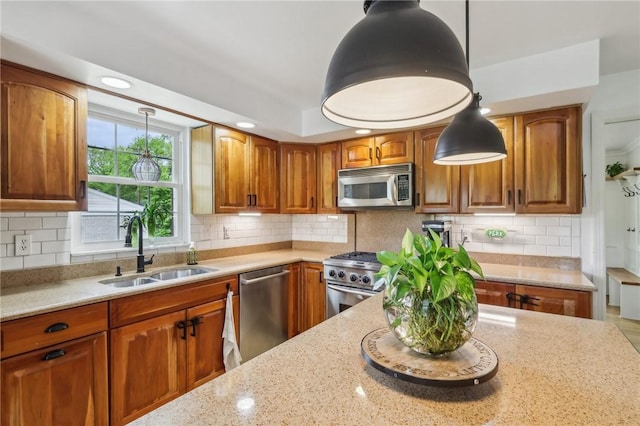 kitchen featuring stainless steel appliances, a sink, light stone countertops, pendant lighting, and recessed lighting