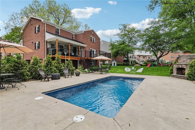 swimming pool with a patio, a yard, and an outdoor stone fireplace