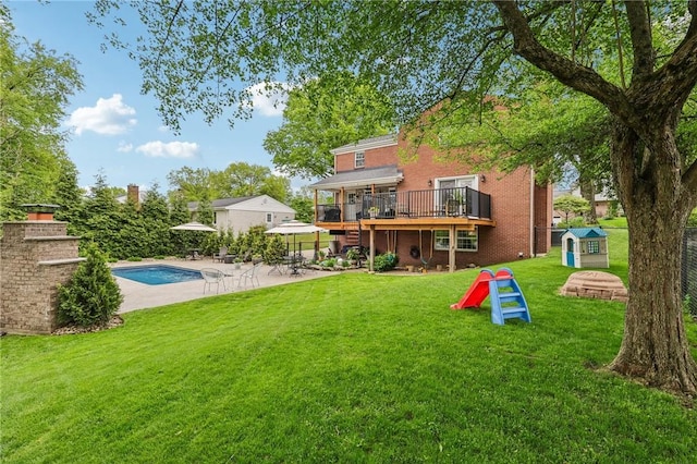 back of property with a shed, a patio area, a yard, a wooden deck, and brick siding