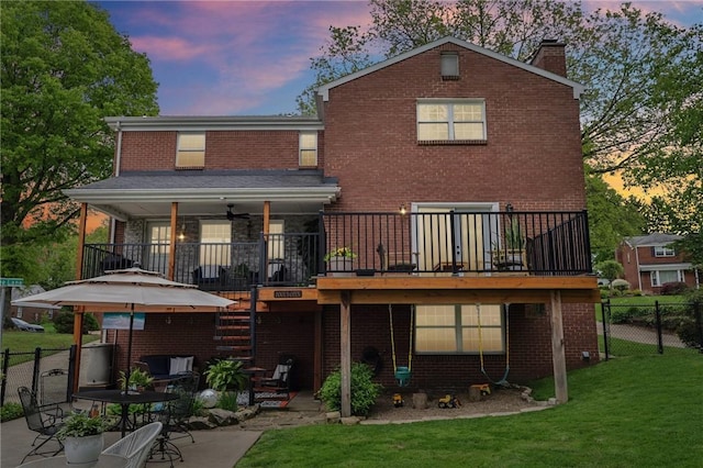 back of house at dusk with brick siding, a chimney, a patio area, a ceiling fan, and stairway