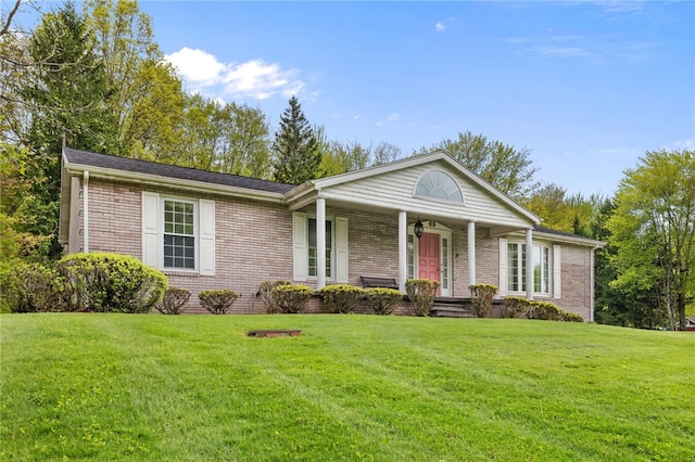 single story home with a porch, a front yard, ceiling fan, and brick siding