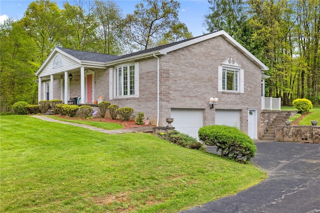 view of front of home featuring covered porch, asphalt driveway, a garage, a front yard, and brick siding