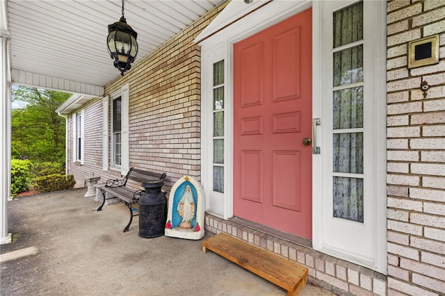 view of exterior entry featuring covered porch and brick siding