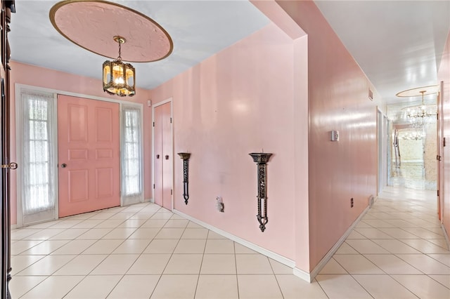 entrance foyer featuring a chandelier, light tile patterned floors, and baseboards