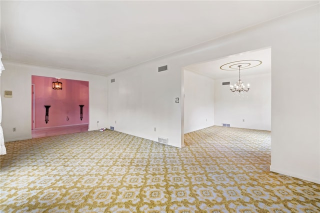 carpeted empty room featuring a chandelier