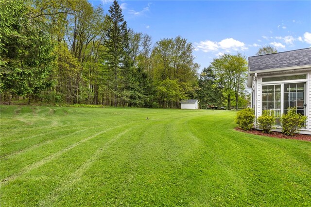 view of green lawn featuring a shed and an outbuilding