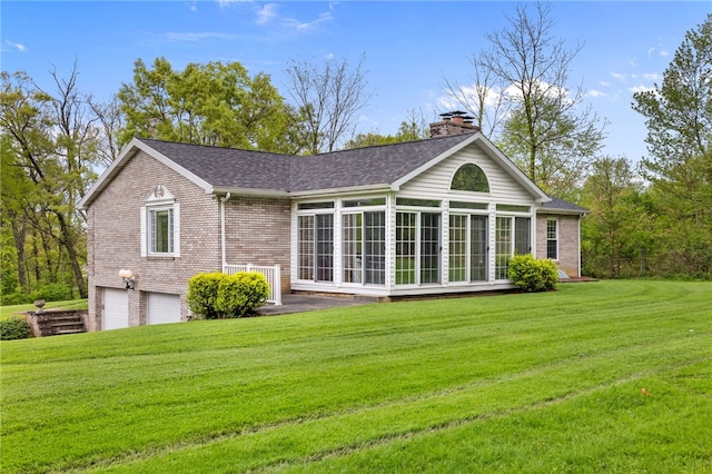 rear view of property featuring a chimney, brick siding, a garage, and a sunroom