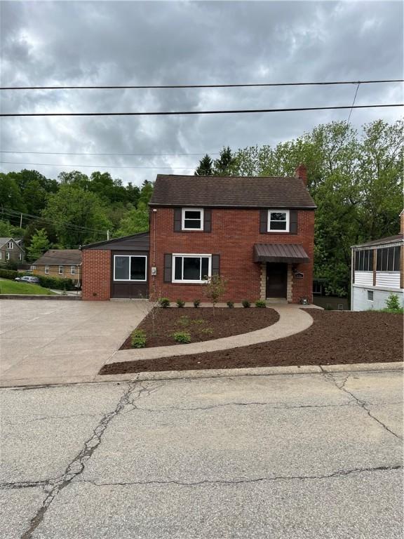 traditional-style home featuring driveway, a chimney, and brick siding