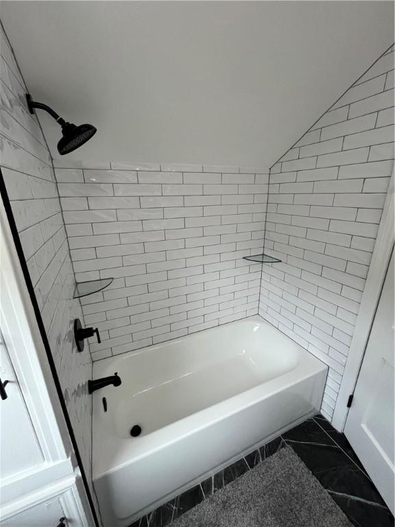 bathroom featuring tub / shower combination and lofted ceiling