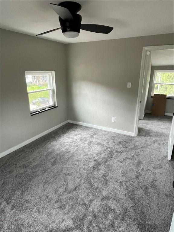 spare room with a ceiling fan, carpet, and baseboards