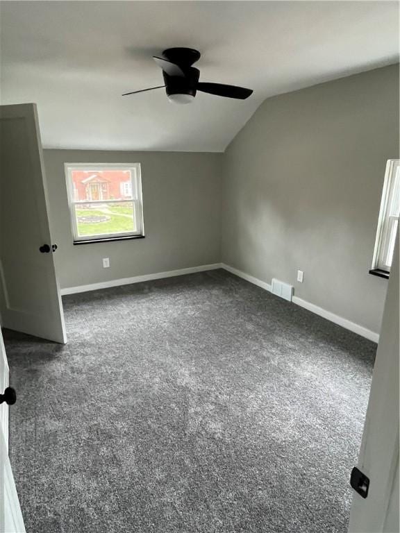 carpeted empty room with vaulted ceiling, a ceiling fan, and baseboards