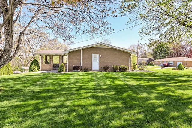 rear view of house featuring a yard and brick siding