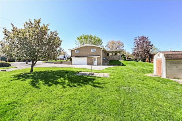 view of green lawn featuring an attached garage, a storage unit, driveway, and an outbuilding