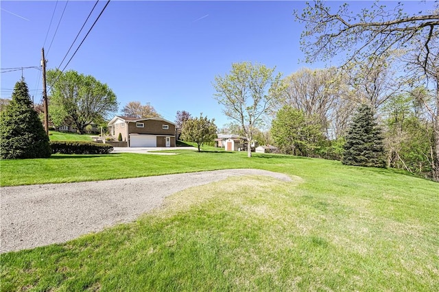 view of green lawn featuring a garage and driveway
