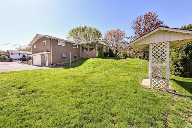 view of green lawn featuring driveway and an attached garage