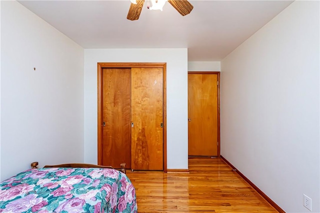 bedroom with light wood finished floors, a closet, ceiling fan, and baseboards