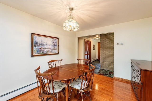 dining space with a chandelier, a baseboard heating unit, baseboards, and light wood-type flooring