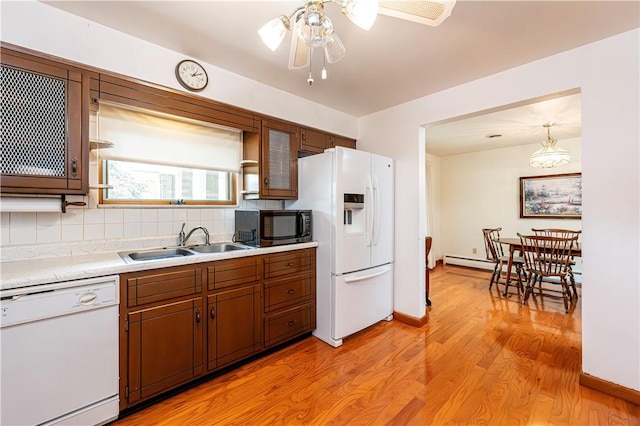 kitchen featuring white appliances, a sink, light countertops, ceiling fan, and backsplash