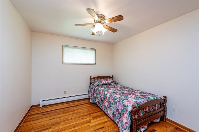 bedroom with a baseboard radiator, wood finished floors, a ceiling fan, and baseboards