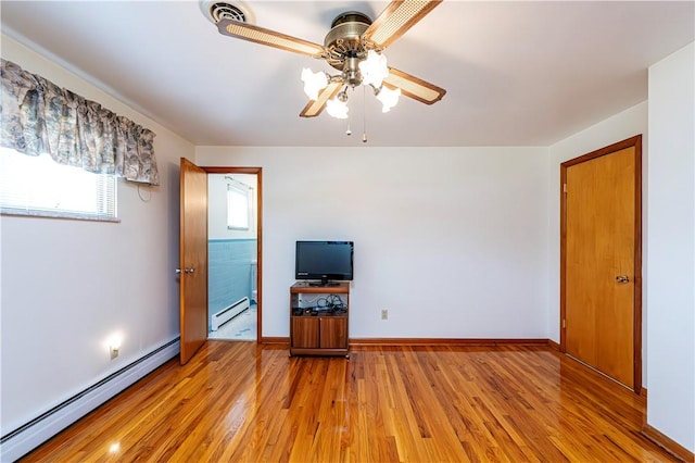 unfurnished living room featuring a baseboard heating unit, ceiling fan, and light wood-type flooring