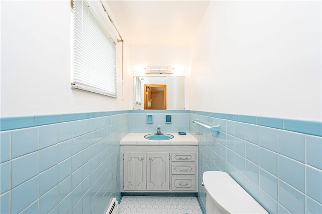 bathroom featuring tile walls, tile patterned flooring, toilet, vanity, and wainscoting