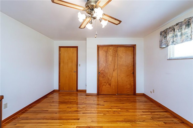 unfurnished bedroom with light wood finished floors, a closet, baseboards, and a ceiling fan