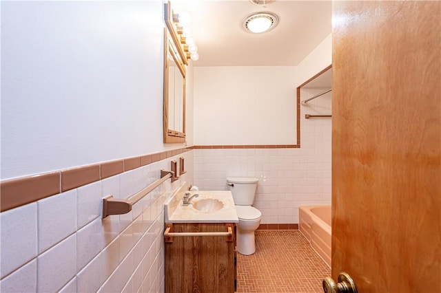 bathroom with tile walls, toilet, vanity, wainscoting, and bathing tub / shower combination