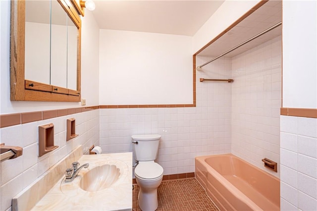 full bath with tile walls, toilet, shower / bathtub combination, a wainscoted wall, and tile patterned flooring