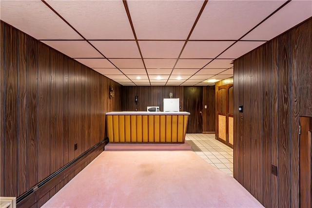 bar area featuring wood walls, a paneled ceiling, a baseboard heating unit, and freestanding refrigerator