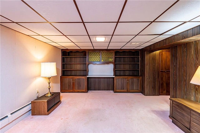 unfurnished room with a baseboard heating unit, carpet floors, and a paneled ceiling