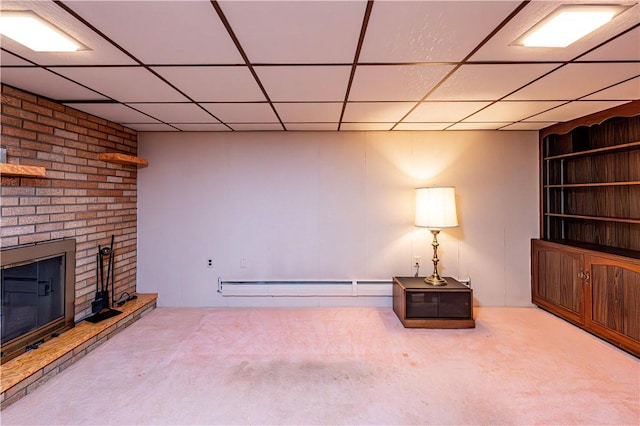 unfurnished room featuring carpet floors, baseboard heating, a fireplace, and a drop ceiling
