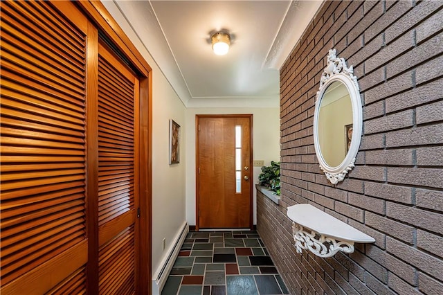 doorway to outside with a baseboard radiator, brick wall, stone finish floors, and baseboards