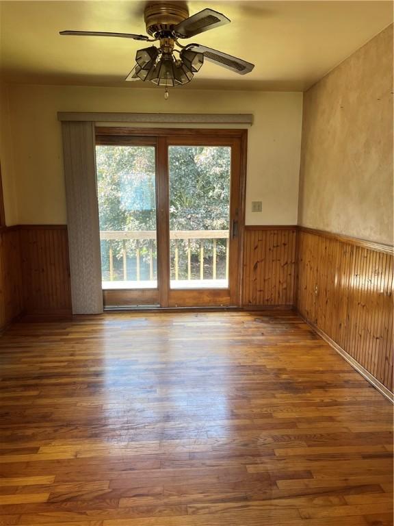 105 Lawrence Ave, Twp Of But Nw, PA 16001 - empty room featuring a wainscoted wall, wood finished floors, ceiling fan, and wood walls