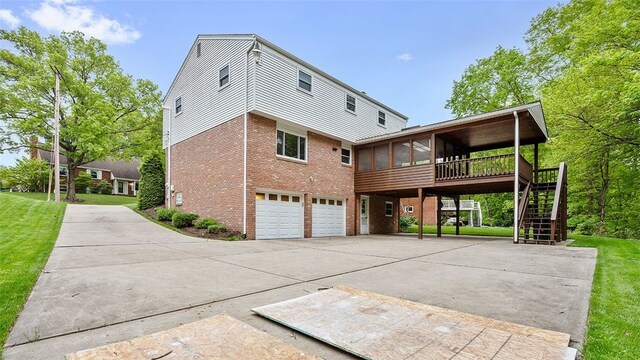 2023 Menold Dr, Mccandless, PA 15101 - rear view of house with a sunroom, driveway, stairs, brick siding, and a garage