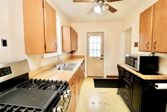 kitchen featuring appliances with stainless steel finishes, a sink, light countertops, light flooring, and ceiling fan