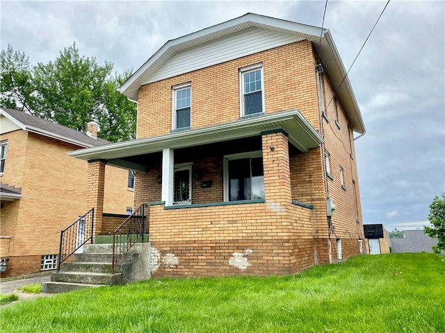 view of front facade featuring brick siding, a front yard, and a porch