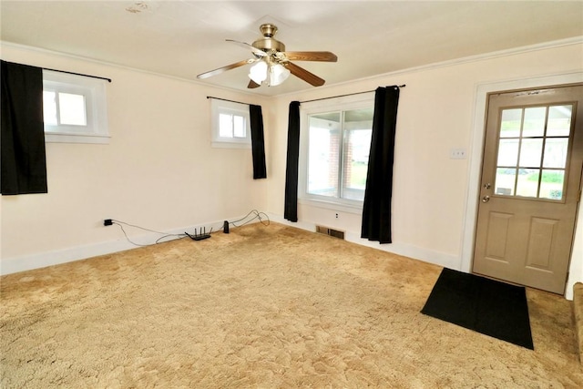 empty room featuring carpet floors, ceiling fan, baseboards, and crown molding