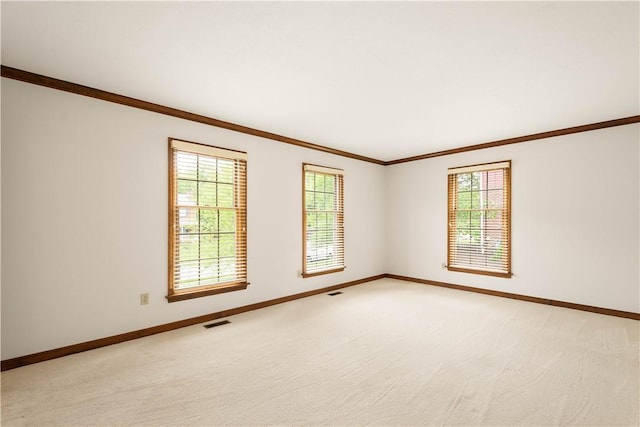 unfurnished room featuring ornamental molding, baseboards, and light carpet