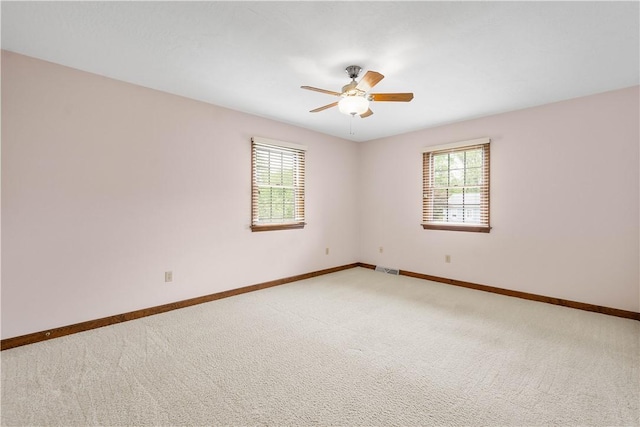 unfurnished room featuring healthy amount of natural light, carpet, baseboards, and ceiling fan