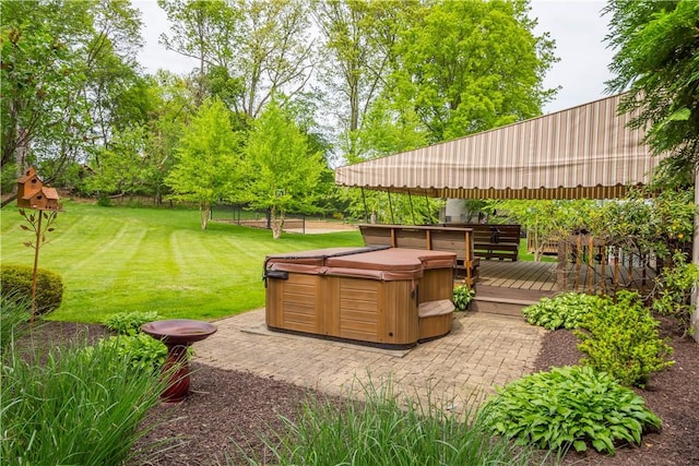 view of grassy yard featuring a hot tub, a deck, and a patio area