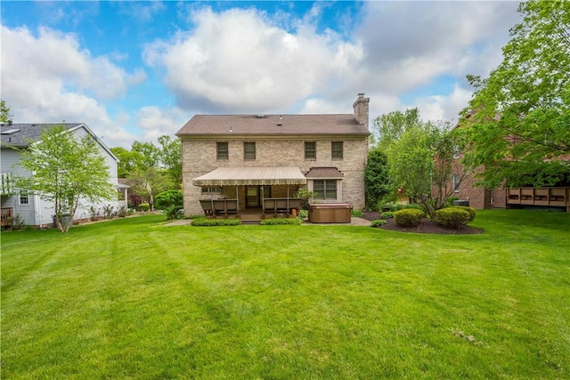 back of property with a hot tub, a chimney, a lawn, and stone siding