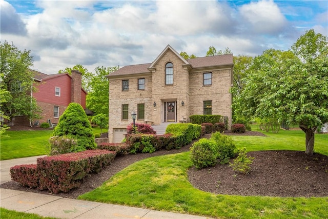 view of front facade featuring a front lawn, an attached garage, and brick siding